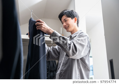 一個年輕人在步入式衣櫥裡挑選衣服（時尚搭配） 97954774