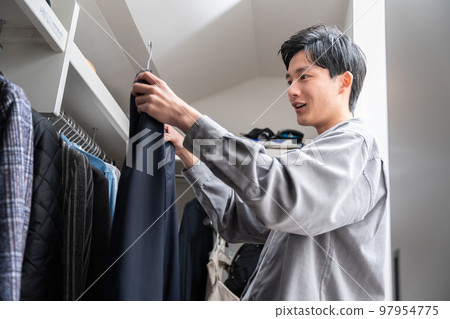 一個年輕人在步入式衣櫥裡挑選衣服（時尚搭配） 97954775