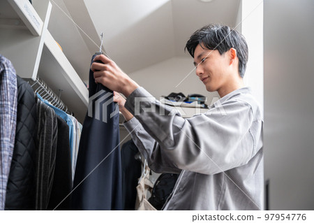 一個年輕人在步入式衣櫥裡挑選衣服（時尚搭配） 97954776
