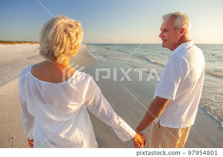 Happy Senior Old Retired Couple Walking Holding Hands on Beach at Sunset Happy Senior Old Retired Couple Walking Holding Hands on Beach at Sunset 97954801