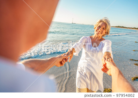 Happy Senior Old Retired Couple Dancing Holding Hands on a Beach Happy Senior Old Retired Couple Dancing Holding Hands on a Beach 97954802