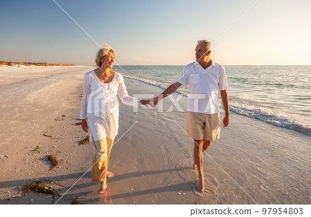 Happy Senior Old Retired Couple Walking Holding Hands on Beach at Sunset Happy Senior Old Retired Couple Walking Holding Hands on Beach at Sunset 97954803