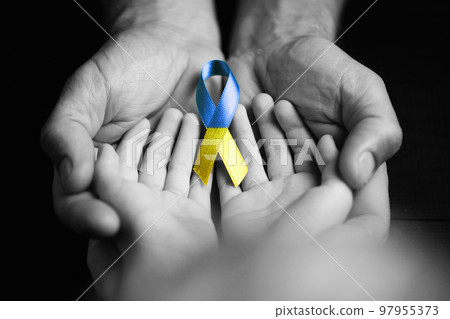 children hands in male hands with ukraine ribbon 97955373