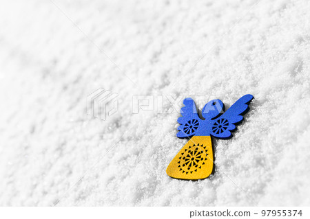 blue and yellow toy angel on white snow 97955374