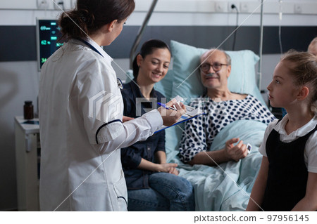 Elderly people care nurse reviewing files of senior male patient bedridden in geriatric hospital. Female general practitioner listening to older hospitalized man symptoms. Elderly people care nurse reviewing files of senior male patient bedridden in geriatric hospital. Female general practitioner listening to older hospitalized man symptoms. 97956145