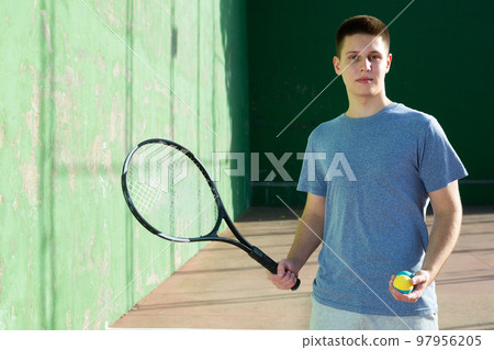 Portrait of caucasian boy standing on frontenis court, holding racket and ball 97956205