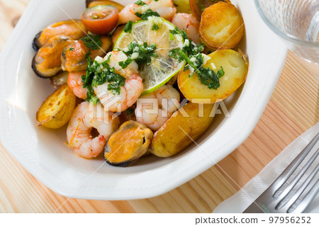 Tasty warm salad with fried potatoes, shrimp and mussels, served at plate Tasty warm salad with fried potatoes, shrimp and mussels, served at plate 97956252