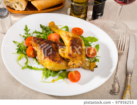 Roasted chicken thighs with arugula and tomatoes. 97956253