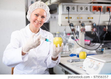 Woman lab technician analyzing apple in laboratory Woman lab technician analyzing apple in laboratory 97956357