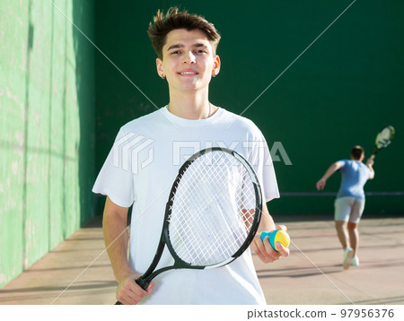 Portrait of caucasian boy standing on frontenis court, holding racket and ball 97956376