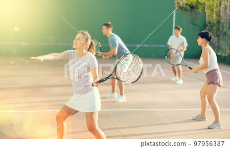 Sportive woman in shorts and t-shirt playing frontenis on court 97956387