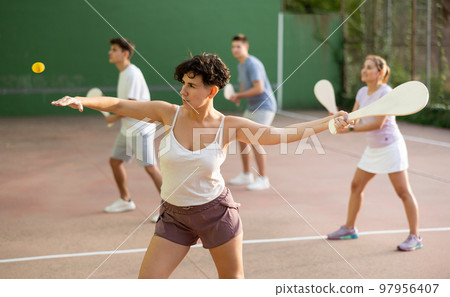 Woman serving ball during frontenis game outdoors Woman serving ball during frontenis game outdoors 97956407