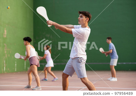 Caucasian teenage boy in sportswear playing paleta fronton on court Caucasian teenage boy in sportswear playing paleta fronton on court 97956489