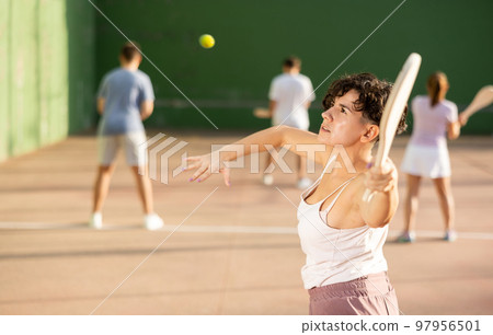 Active womans with enthusiasm playing paleta fronton group on outdoor court Active womans with enthusiasm playing paleta fronton group on outdoor court 97956501