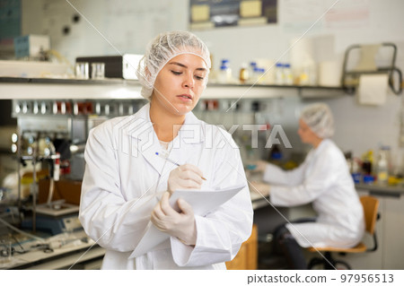 Portrait of young woman lab technician writing report on results of chemical experiments in research center 97956513