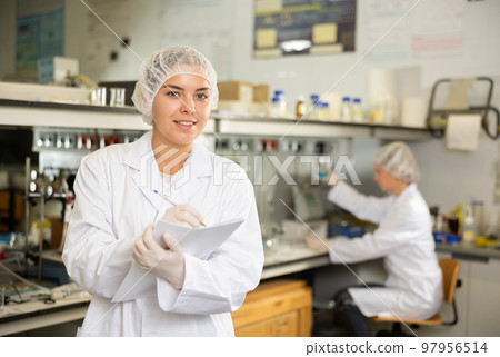 Professional scientist woman writing notes or research report during experiment in science laboratory 97956514