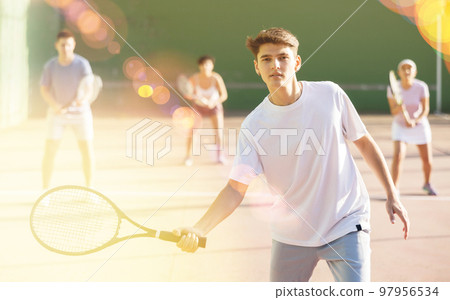 Male sportsman preparing to hit ball with racket. Frontenis game on outdoor court 97956534