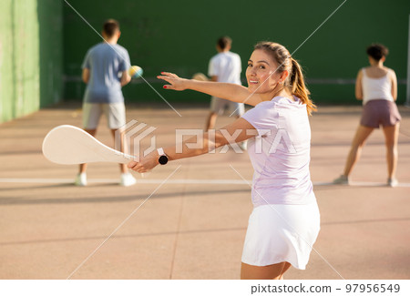 Portrait of sporty girl playing paleta fronton on outdoor court, ready to hit ball. Healthy and active lifestyle concept 97956549