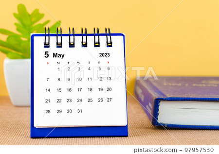 The May 2023 Monthly desk calendar for 2023 with a book on yellow background. 97957530