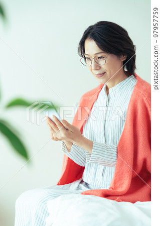 Middle woman operating a smartphone Middle woman operating a smartphone 97957759