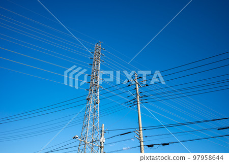 A clear sky looking up at the power transmission tower that supports the electric wires and high-voltage transmission lines in the residential area 97958644