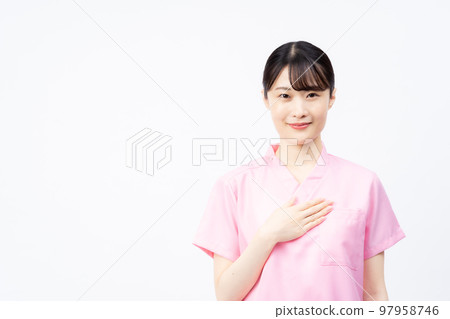 A young female nurse wearing a pink scrub with her hand on her chest 97958746