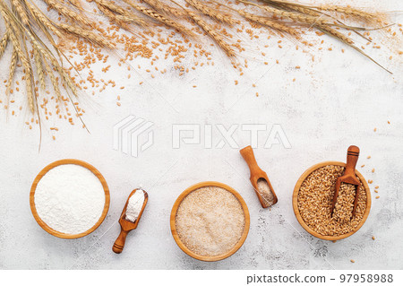 Wheat grains , brown wheat flour and white wheat flour in wooden bowl set up on white concrete background. Wheat grains , brown wheat flour and white wheat flour in wooden bowl set up on white concrete background. 97958988