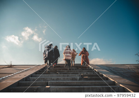 Five friends happily run up the stairs under the blue sky 97959432