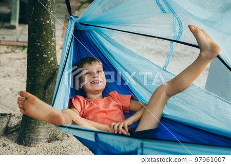 Smile child boy lie rest back hammock. Happy childhood daydream. Bare feet up sole feet toes hand 97961007