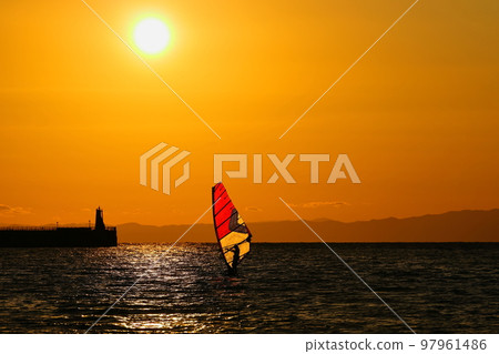 A young man who enjoys windsurfing in the orange sky and sea at dusk on the Zushi coast in winter A young man who enjoys windsurfing in the orange sky and sea at dusk on the Zushi coast in winter 97961486