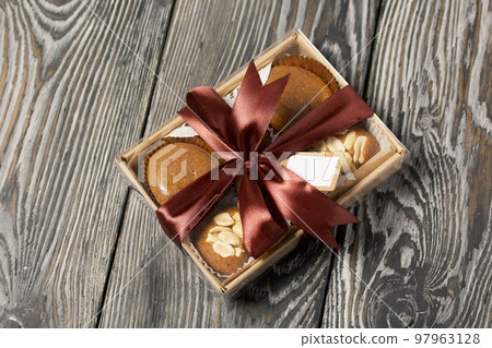 Homemade caramel. Brown caramel candies. Creamy sweets with peanuts. On pine boards. Packed in a box and tied with a ribbon. 97963128