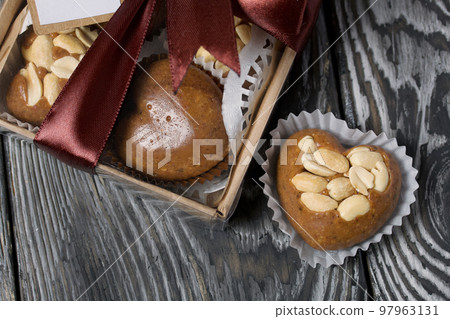Homemade caramel. Brown caramel candies. Creamy sweets with peanuts. On pine boards. Some of them are packed in a box and tied with a ribbon. Homemade caramel. Brown caramel candies. Creamy sweets with peanuts. On pine boards. Some of them are packed in a box and tied with a ribbon. 97963131