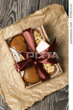 Homemade caramel. Brown caramel candies. Creamy sweets with peanuts. On pine boards. Packed in a box and tied with a ribbon. 97963142