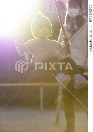 3 year old girl playing on a swing in the park 97964292