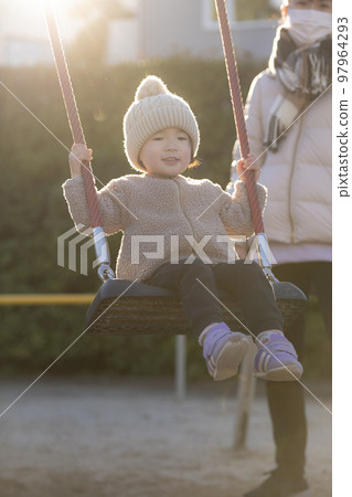 3 year old girl playing on a swing in the park 97964293