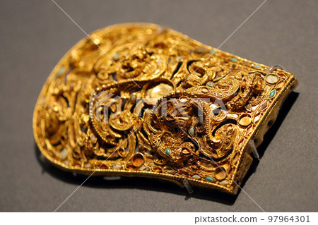 A close-up image of an elaborately decorated golden belt buckle from the Three Kingdoms period of ancient China. A close-up image of an elaborately decorated golden belt buckle from the Three Kingdoms period of ancient China. 97964301