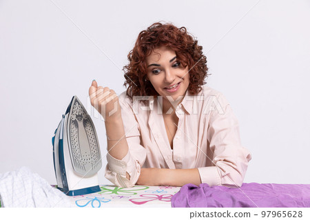 A girl nervous about the iron and all the work involved in ironing men's shirts. 97965628