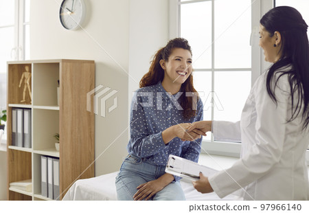 Happy grateful patient shakes hands with her doctor after consultation meeting in hospital office. Happy grateful patient shakes hands with her doctor after consultation meeting in hospital office. 97966140