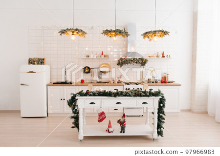 Interior of a bright kitchen with a table in a Scandinavian style island, decorated for Christmas and New Year 97966983