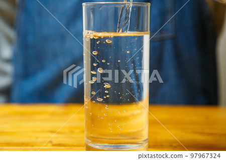 Water being poured into a cup on the table 97967324
