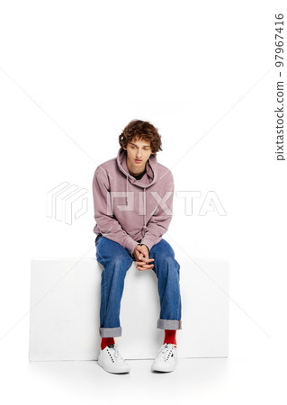 Portrait of young unhappy boy sitting over white background. Looking sad, thoughtful and lonely Portrait of young unhappy boy sitting over white background. Looking sad, thoughtful and lonely 97967416