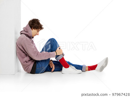 Portrait of young boy in casual clothes sitting with thoughtful face over white background. feeling depression and emotional breakdown Portrait of young boy in casual clothes sitting with thoughtful face over white background. feeling depression and emotional breakdown 97967428