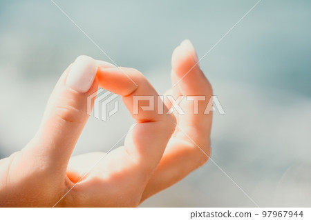 Close up Yoga Hand Gesture of Woman Doing an Outdoor meditation. Blurred sea background. Woman on yoga mat in beach meditation, mental health training or mind wellness by ocean, sea Close up Yoga Hand Gesture of Woman Doing an Outdoor meditation. Blurred sea background. Woman on yoga mat in beach meditation, mental health training or mind wellness by ocean, sea 97967944