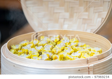 Dim Sim (Kanom jeeb) the chinese steamed dumpling on banana leaf in bamboo wicker plate for appetizer of seminar. 97969234