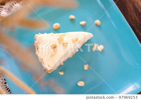 Coconut Cream Pie in the turquoise dish on the wood table that topping with macademia. Shooting in the sunlight. 97969253