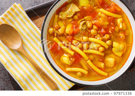 Canarian soup with meat, pasta, chickpeas and vegetables close-up on a plate. horizontal top view 97971336