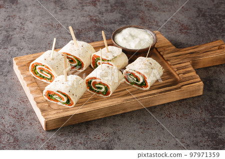 Tasty rolls with salmon, cheese and vegetables for a brunch closeup on the board. Horizontal Tasty rolls with salmon, cheese and vegetables for a brunch closeup on the board. Horizontal 97971359