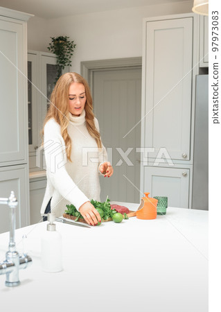Young woman is preparing in the kitchen. Healthy Food. Salad. Diet. Dieting Concept. Healthy Lifestyle. Cooking At Home. Prepare Food. Cutting ingredients on the table 97973083