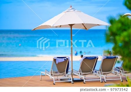 Umbrellas and deck chairs by the pool in an Asian luxury resort hotel 97973542