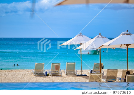 Umbrellas and deck chairs on the white sandy beach of an Asian luxury resort hotel Umbrellas and deck chairs on the white sandy beach of an Asian luxury resort hotel 97973610